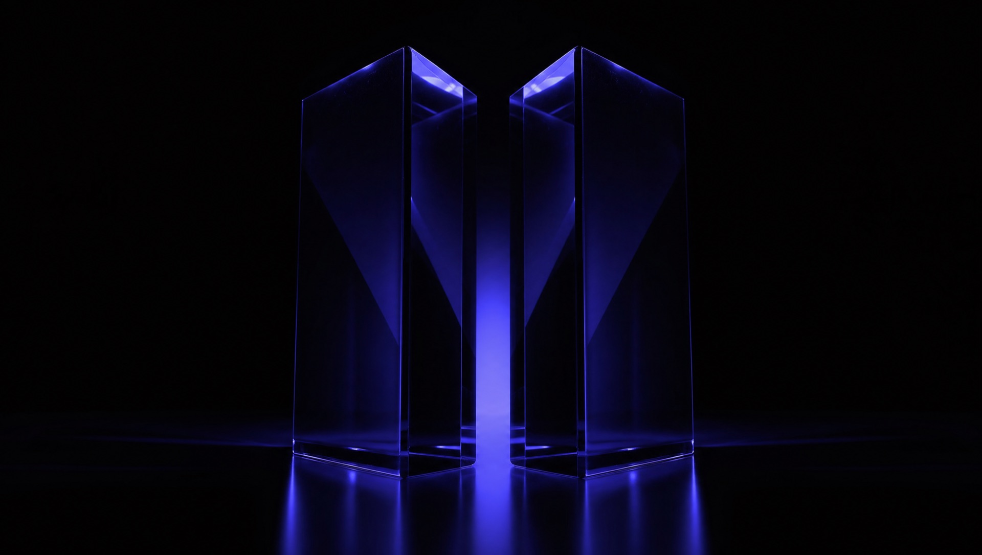 Two glass monoliths facing each other on a dark reflective surface